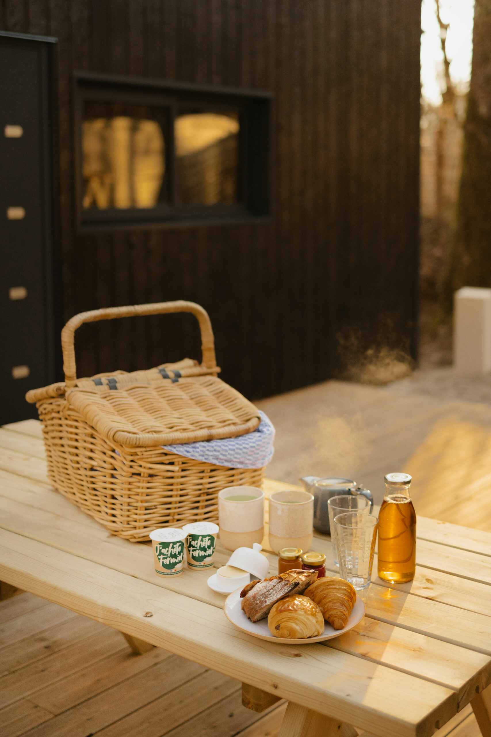 Panier, tasses, jus et viennoiseries sur la table du petit déjeuner Parenthèse